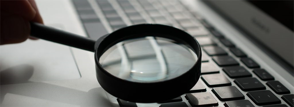 Magnifying glass above keyboard of laptop.